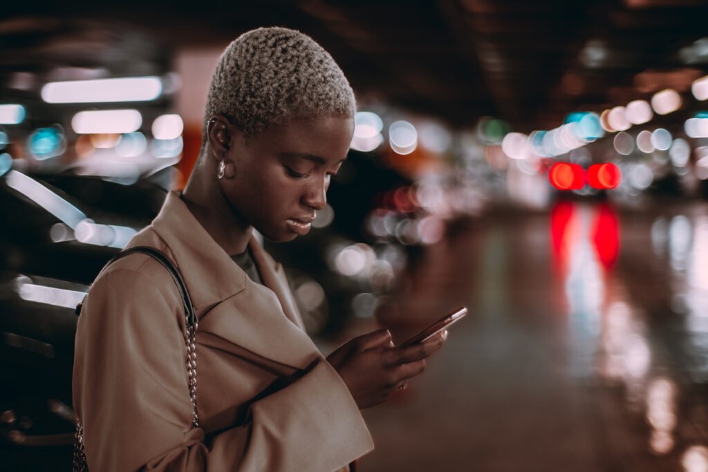Black girl using cellphone, parking